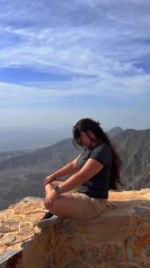 Kız dağda oturuyor.