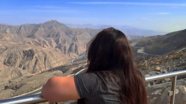 Genç bir kadın dağların tepesinde.