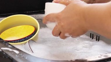 Bulaşık yıkayan bir kadının ellerine yakın çekim.
