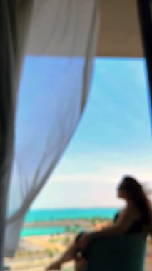 Arka plan bulanık. Deniz manzaralı, deniz manzaralı, güneş pencerenin arkasında, kız bakıyor...