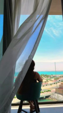 Kumsalda kitabı olan genç bir kadın.