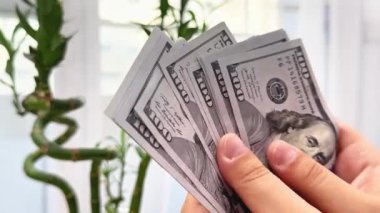 Kadın elinde para tutuyor ve sayıyor.