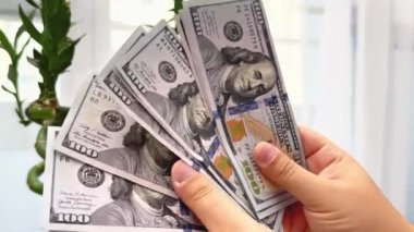 Kadın elinde dolar banknotları tutuyor ve para sayıyor.