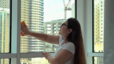 Camları siliyorum. Evde temizlik hizmeti. Sabun solüsyonu pencereye sıçradı. Temiz cam. Camları silmek için kazıyıcı. Ev hanımı pencereyi temizler. Yatay video. Yüksek kalite 4k görüntü