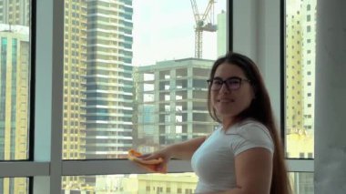 Camları siliyorum. Evde temizlik hizmeti. Sabun solüsyonu pencereye sıçradı. Temiz cam. Camları silmek için kazıyıcı. Ev hanımı pencereyi temizler. Yatay video. Yüksek kalite 4k görüntü