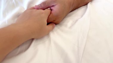 Beyaz bir yatak tutan bir elin yakınına.