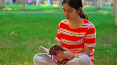Genç kız parkta kitap okuyor.