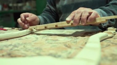 Bir marangoz bir el testeresiyle tahtayı testereyle keser. Katı ahşap mobilya yapmak için bir atölyede tahta işleme süreci. Tecrübeli bir marangoz otantik bir atölyede.