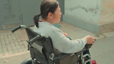 Tekerlekli sandalyedeki yaşlı bayan oturma odasında televizyon izliyor elinde uzaktan kumandalı televizyon kanalı değiştiriyor. Büyükannem televizyonu açıyor. Yüksek kalite 4k görüntü