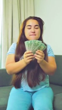Dikey görüntüler, gülümseyen kadını heyecanlandırdı. Nakit para, 1000 Amerikan doları banknotlar, yakın çekim, gelir, kazanan ve iş konsepti. Yüksek kalite 4k görüntü