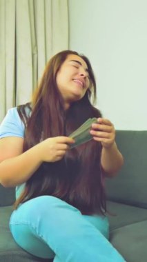Dikey görüntüler, gülümseyen kadını heyecanlandırdı. Nakit para, 1000 Amerikan doları banknotlar, yakın çekim, gelir, kazanan ve iş konsepti. Yüksek kalite 4k görüntü