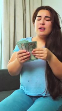 Dolarları tutan ve baş parmağını gösteren genç bir kadın.