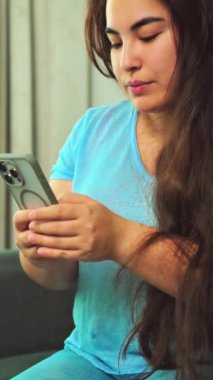 Evde akıllı telefon kullanan genç ve güzel bir kadın.