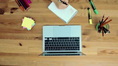 Bir dizüstü bilgisayar, not defteri, kalem, gözlük ve diğer öğelerle masaüstü görünümü