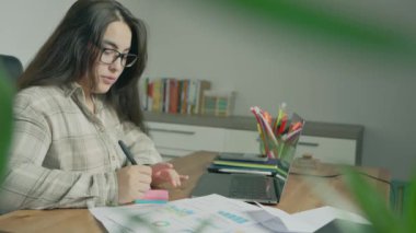 Evdeki defterde yazan genç bir kadın.