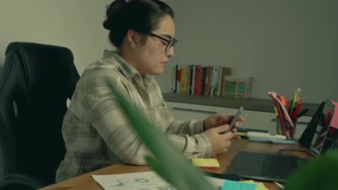 Ofis masasında çalışan Asyalı kadın.