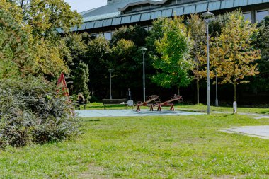 Şehir parkının yolu boyunca sakin ahşap bir bank. Yeşil çimenli olgun yaprak döken ağaçlar onu dinlenmek için büyülü bir yer haline getiriyor. Yüksek kalite fotoğraf