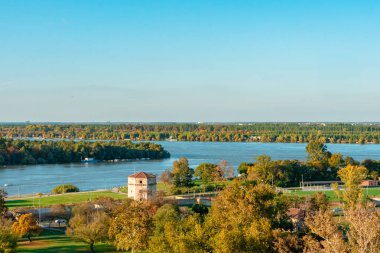Gün batımında şehrin güzel manzarası. Yüksek kaliteli fotoğraf, Tuna Nehri arka planda yüksek ağaçların kayan tepelerle buluştuğu bir manzaranın içinde kıvrılır. Gökyüzü 