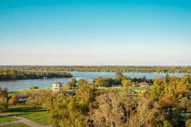 Gün batımında şehrin güzel manzarası. Yüksek kaliteli fotoğraf, Tuna Nehri arka planda yüksek ağaçların kayan tepelerle buluştuğu bir manzaranın içinde kıvrılır. Gökyüzü 