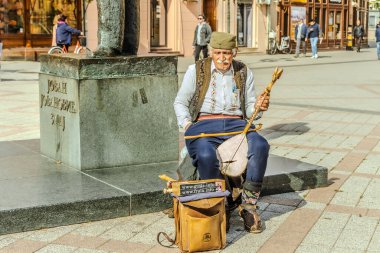 Gitarlı bir sokak müzisyeni ve sırt çantalı bir adam.
