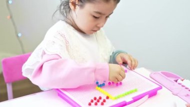 Cımbız kullanarak şeffaf çerçevedeki renkli silindirik boncukları düzenlemek, yaratıcılık kavramı, iyi motor becerilerin geliştirilmesi, konsantrasyon ve koordinasyon. Yüksek kalite 4k