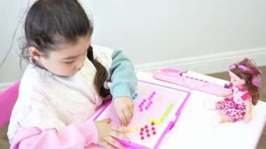 Cımbız kullanarak şeffaf çerçevedeki renkli silindirik boncukları düzenlemek, yaratıcılık kavramı, iyi motor becerilerin geliştirilmesi, konsantrasyon ve koordinasyon. Yüksek kalite 4k