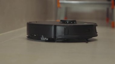 Yuvarlak robot süpürgesi banyoda düzenli olarak hareket ediyor, sensörleri toz ve saç taraması yapıyor. Yüksek kalite 4k görüntü