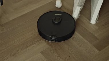 Yuvarlak robot süpürgesi banyoda düzenli olarak hareket ediyor, sensörleri toz ve saç taraması yapıyor. Yüksek kalite 4k görüntü