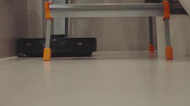 Yuvarlak robot süpürgesi banyoda düzenli olarak hareket ediyor, sensörleri toz ve saç taraması yapıyor. Yüksek kalite 4k görüntü
