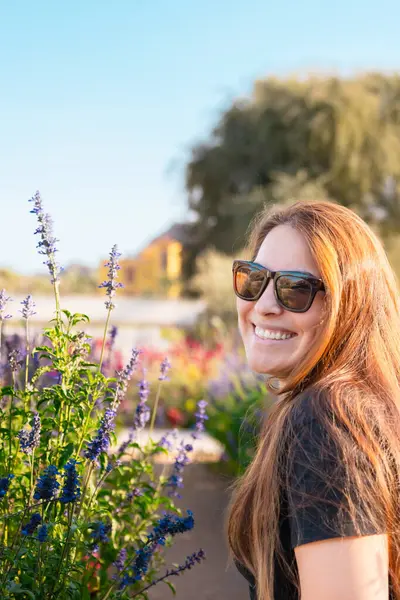 Çiçek açan bahar bahçesinde kokunun tadını çıkaran genç bir kadın. Gençlik, aşk, moda ve yaşam tarzı kavramı. Yüksek kalite fotoğraf