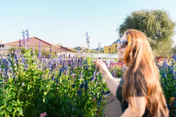 Çiçek açan bahar bahçesinde kokunun tadını çıkaran genç bir kadın. Gençlik, aşk, moda ve yaşam tarzı kavramı. Yüksek kalite fotoğraf