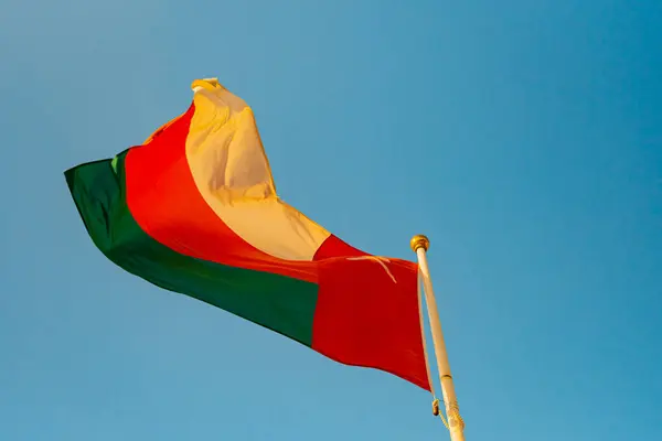 Umman bayrağı rüzgarda, ulusal gurur ve kimliği simgeleyen canlı mavi gökyüzüne karşı zarif bir şekilde dalgalanıyor. Yüksek kalite fotoğraf