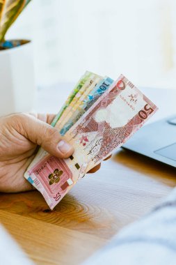 Bir adamın elini kapat ve parayı say Katar parası. Yüksek kalite fotoğraf