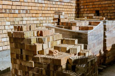 İnşaat malzemeleri yerde, kırmızı tuğlalar istiflenmiş. Yüksek kaliteli seramik tuğla mat, kırmızımsı, gözenekli kırık. Brick temel atmak için kullanıldı. Hırdavatçıdan inşaat malzemeleri al. Yüksek kalite fotoğraf