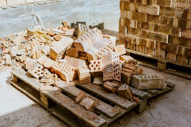 İnşaat malzemeleri yerde, kırmızı tuğlalar istiflenmiş. Yüksek kaliteli seramik tuğla mat, kırmızımsı, gözenekli kırık. Brick temel atmak için kullanıldı. Hırdavatçıdan inşaat malzemeleri al. Yüksek kalite fotoğraf