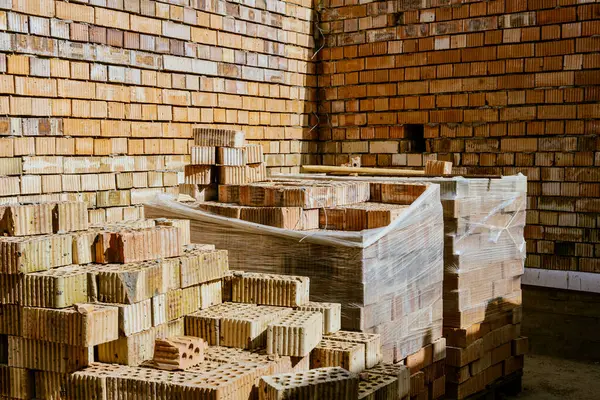 İnşaat malzemeleri yerde, kırmızı tuğlalar istiflenmiş. Yüksek kaliteli seramik tuğla mat, kırmızımsı, gözenekli kırık. Brick temel atmak için kullanıldı. Hırdavatçıdan inşaat malzemeleri al. Yüksek kalite fotoğraf