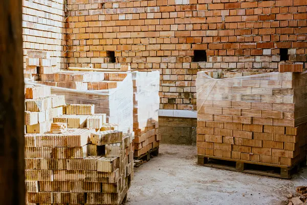 İnşaat malzemeleri yerde, kırmızı tuğlalar istiflenmiş. Yüksek kaliteli seramik tuğla mat, kırmızımsı, gözenekli kırık. Brick temel atmak için kullanıldı. Hırdavatçıdan inşaat malzemeleri al. Yüksek kalite fotoğraf