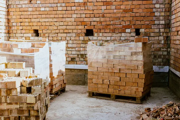 İnşaat malzemeleri yerde, kırmızı tuğlalar istiflenmiş. Yüksek kaliteli seramik tuğla mat, kırmızımsı, gözenekli kırık. Brick temel atmak için kullanıldı. Hırdavatçıdan inşaat malzemeleri al. Yüksek kalite fotoğraf