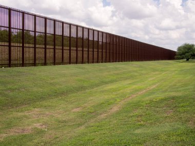 Standing tall and imposing, the rusty steel fence on the USA-Mexico border in Laredo, Texas serves as a visual reminder of the complex relationship between the two neighboring countries. The fence, which stretches for many miles in either direction,  clipart