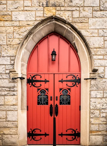 This photo highlights the bold and eye-catching red door of the Southminster Presbyterian Church in Mt Lebanon, Pennsylvania, with its intricate metal mountings. The door serves as a focal point of the church\'s stunning architecture and serves as an