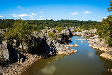 Maryland, ABD 'deki Great Falls yakınlarındaki Potomac Nehri' nin sakinliğini deneyin. Nehrin bu sakin ve huzurlu kesimi yoğun şehir hayatından mükemmel bir kaçış sağlıyor. Kristal berrak sular çevredeki yemyeşil suları yansıtıyor.