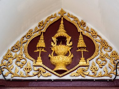 Wat Arun Tapınağı, Bangkok, Tayland 'daki bir kapının üzerinde kırmızı ve beyaz arka planda karmaşık altın süsler. Süslü dekorasyonlarda tapınağın zengin kültürel ve dini mirası, karmaşık desenler ve zarif işçilikle gözler önüne seriliyor.