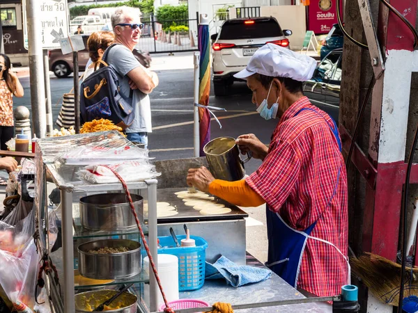 在泰国曼谷繁华的街道上 令人垂涎欲滴的平底锅 芬芳的香料和熟练的街头厨师结合在一起 形成了一个令人垂涎欲滴的景象 这张照片以好奇的游客为背景 捕捉了城市街道的活力和活力 — 图库照片