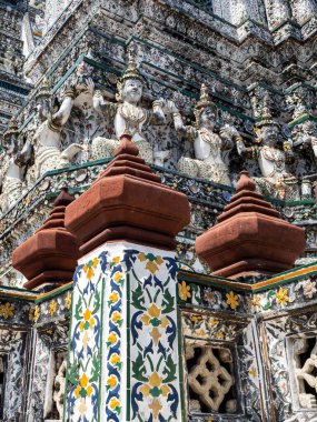 Bangkok 'un Wat Arun Tapınağı' nın nefes kesici güzelliğini tecrübe edin. Çarpıcı heykeller ve canlı kırmızı piramitlerle süslenmiş cephenin karmaşık ayrıntıları tapınağın zengin kültür mirası ve süslü mimarisine hitap ediyor. Bu resim onu yakalar.