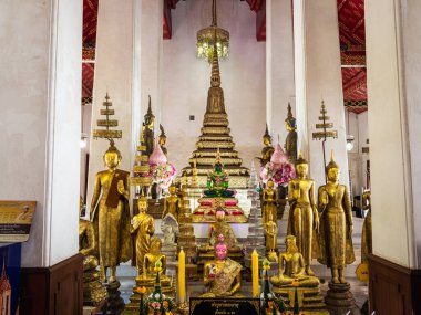 Bangkok, Tayland 'daki Şafak Tapınağı olarak da bilinen görkemli Wat Arun Tapınağı' nın içindeki altın Buda heykellerinin ışıldayan güzelliğine bakın. Bu çarpıcı fotoğraf, saygıdeğer tapınağın karmaşık detaylarını ve huzurlu atmosferini kaydediyor.