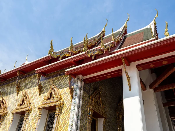 Bangkok, Wat Arun Tapınağı 'ndaki binalardan birinin dekoratif mimarisi. Ön cephe ve çatıdaki çarpıcı kırmızı ve altın ayrıntılar bir canlılık ve bolluk hissi yaratıyor. Tarih ve c açısından zengin geleneksel Tayland tasarımının çarpıcı bir örneği.