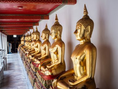 Bangkok, Tayland 'daki Wat Pho Tapınağı' nın duvarını süsleyen altın Buda heykellerinin çarpıcı bir görüntüsü. Heykellerin karmaşık dizaynları ve pırıl pırıl altın yüzeyi hayranlık ve merak uyandırıyor, ziyaretçileri düşünmeye davet ediyor ve...