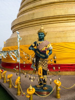 Yakından yakalanan bir heykel, tapınağın yaldızlı kulesinin altında duruyor. Wat Saket 'in tepesinde, Tayland, Bangkok' taki Altın Dağ 'da..