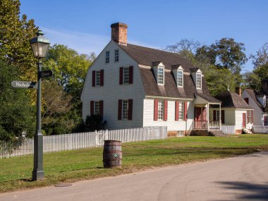 Zarif beyaz koloni evi, çift katlı tasarım, ahşap fıçı, büyüleyici beyaz çit, sokak tabelaları, klasik lamba direği, büyüleyici Williamsburg, Virginia 'da canlı mavi gökyüzüne karşı dizilmiş..