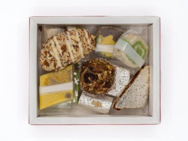 Beyaz bir arka planda izole edilmiş çeşitli Hint ghee tatlılarıyla dolu bir kutunun üst görüntüsü..